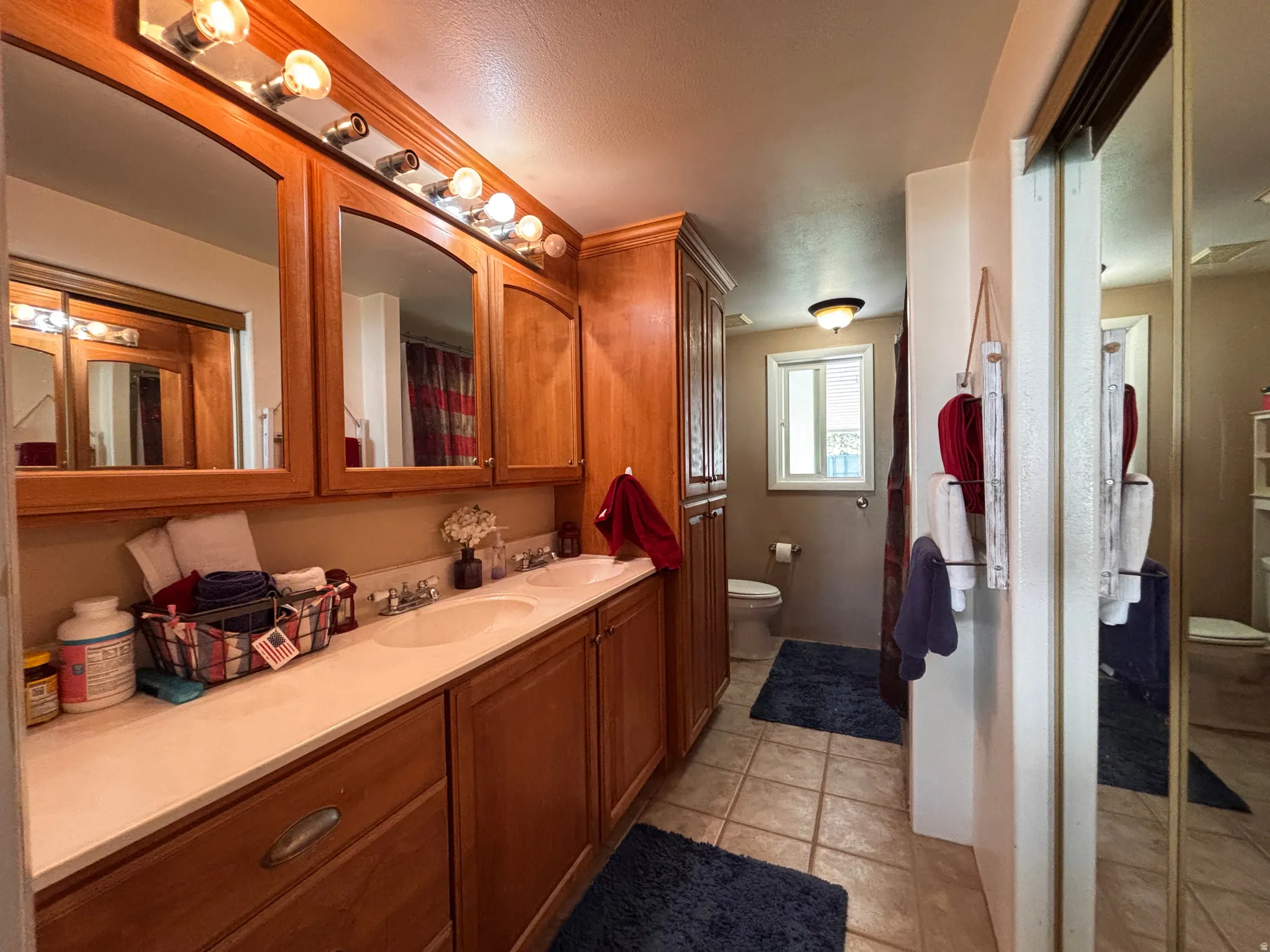 Bathroom featuring a dual vanity with light-tone countertops and wood cabinetry