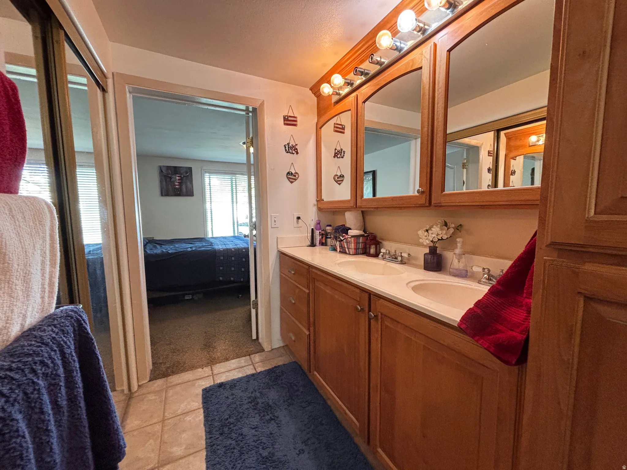 Bathroom vanity featuring dual sinks with built-in cabinetry, arched mirrors, and a multi-bulb light fixture