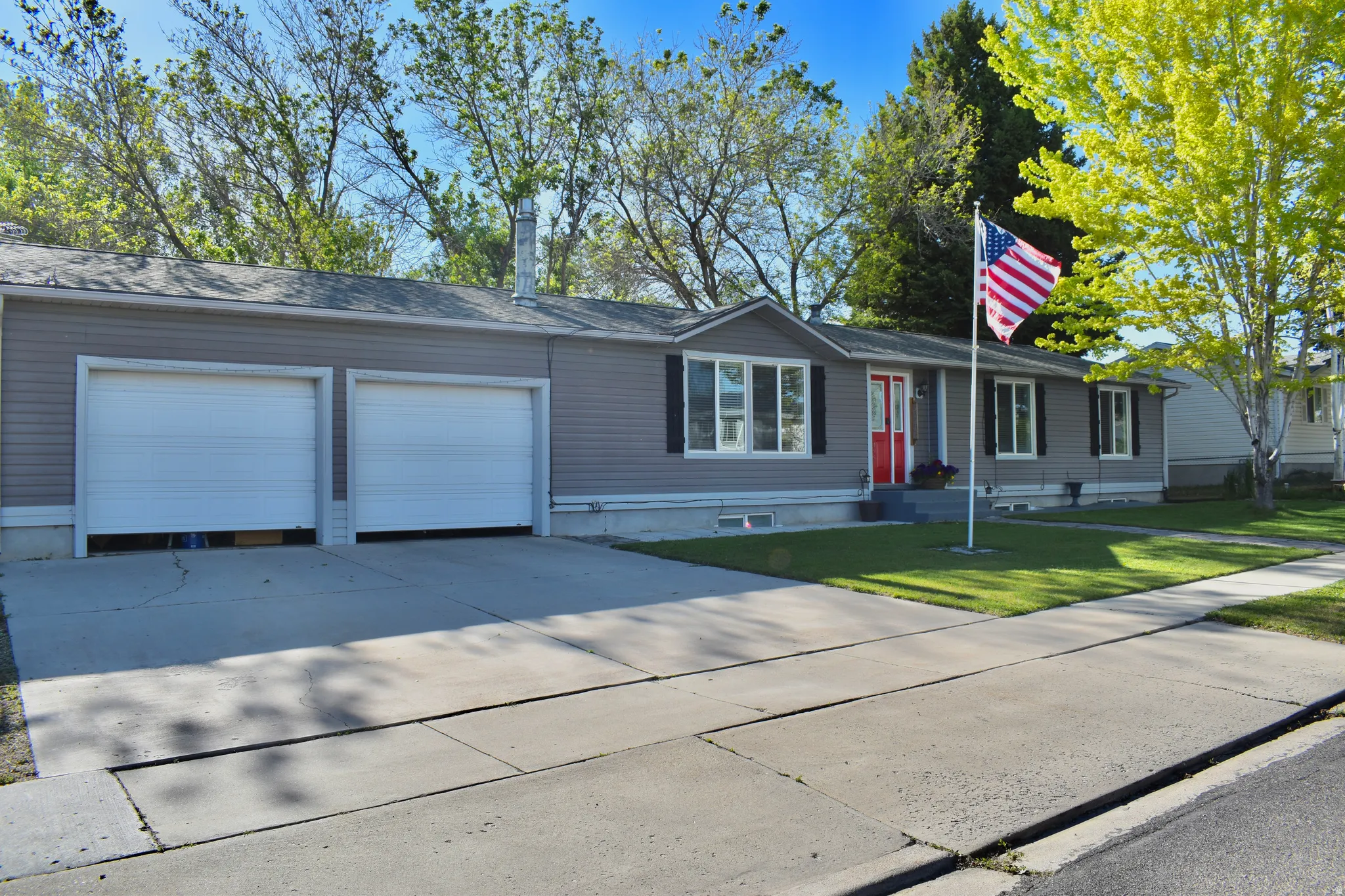 Ranch-style residence featuring grey siding and a red front door