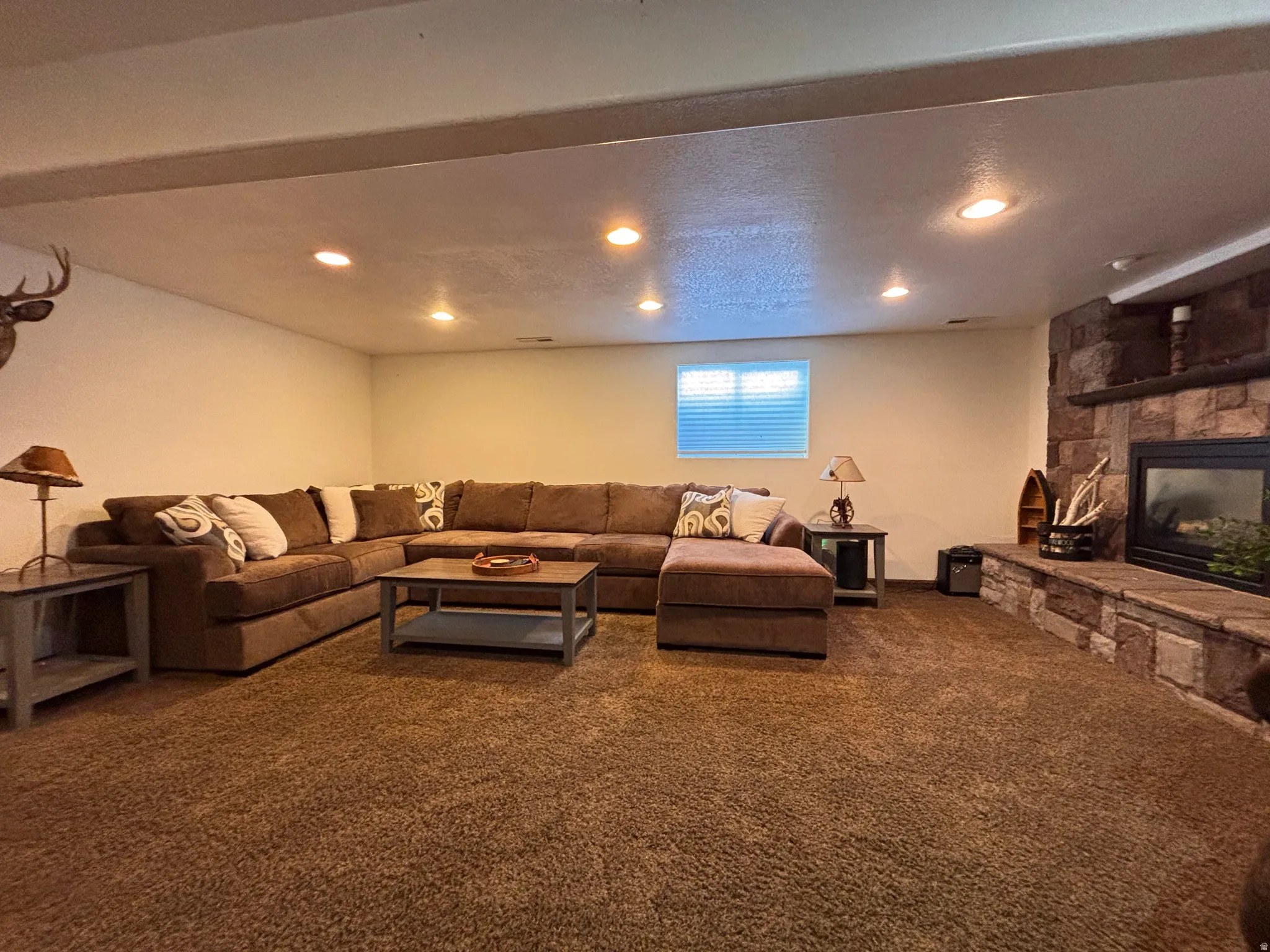 Spacious room featuring broadloom carpeting and a stone-faced fireplace with hearth