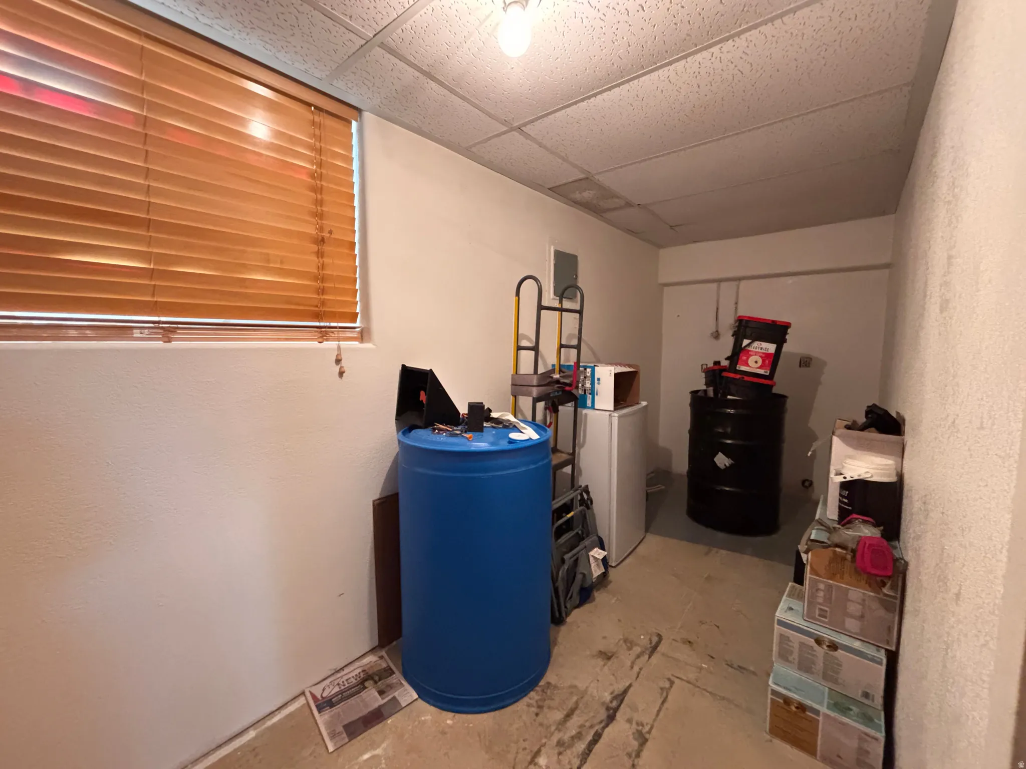 Room featuring a dropped ceiling, a window with wood-finish blinds, and painted walls