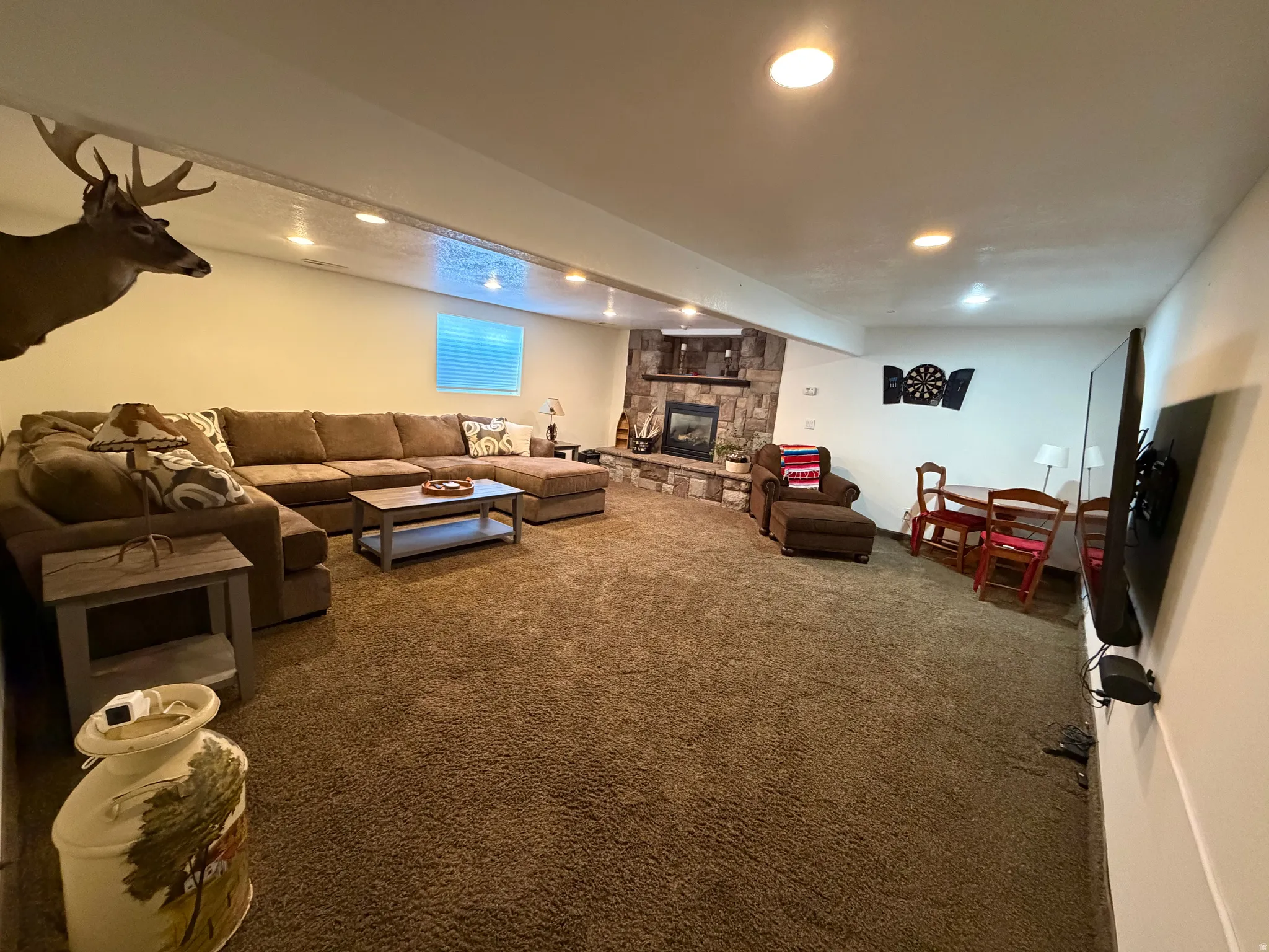Spacious living area featuring recessed lighting, a stone-accented fireplace, and a built-in entertainment niche