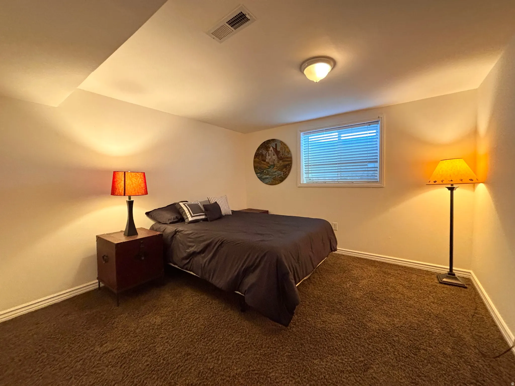 Bedroom featuring plush brown carpeting, a window with blinds, and white baseboards