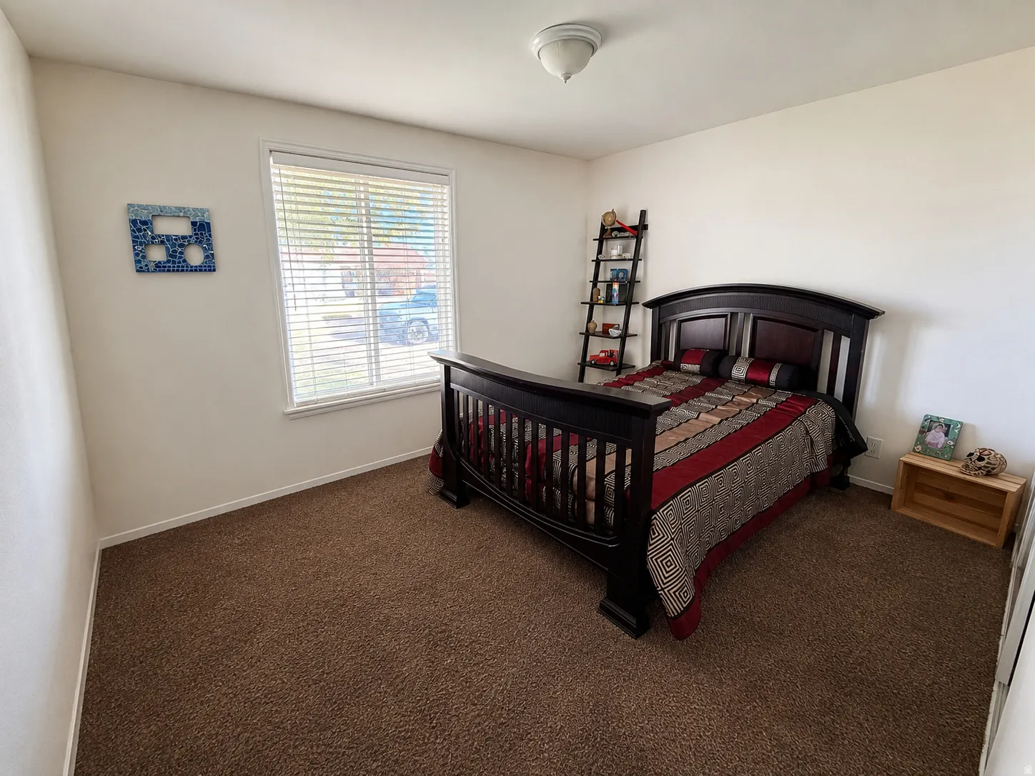 Room featuring a large window with white blinds, neutral wall paint, and brown carpet flooring
