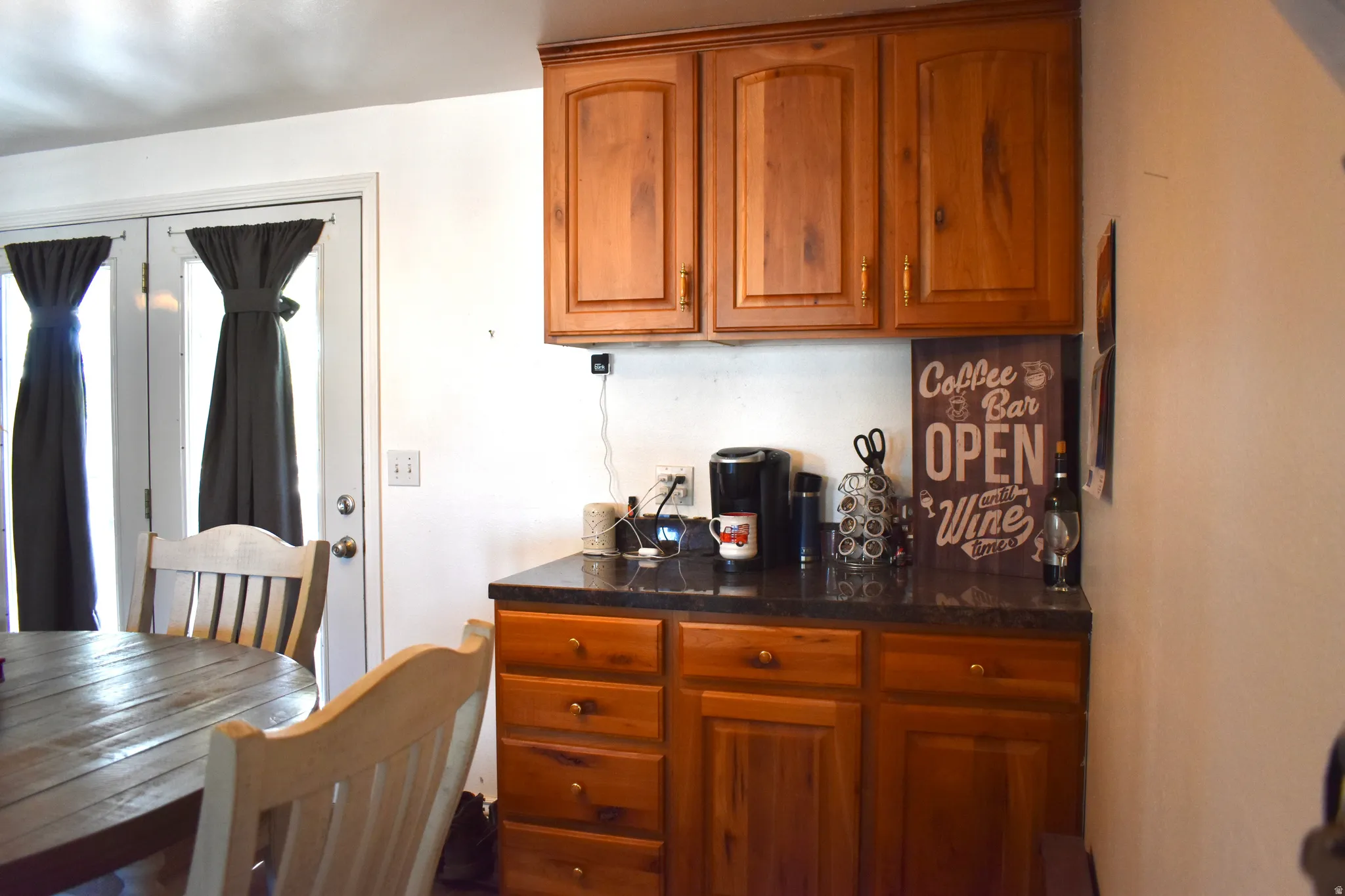 Built-in cabinetry featuring wood-finish doors and drawers, dark stone-finish countertops, and an upper cabinet bank