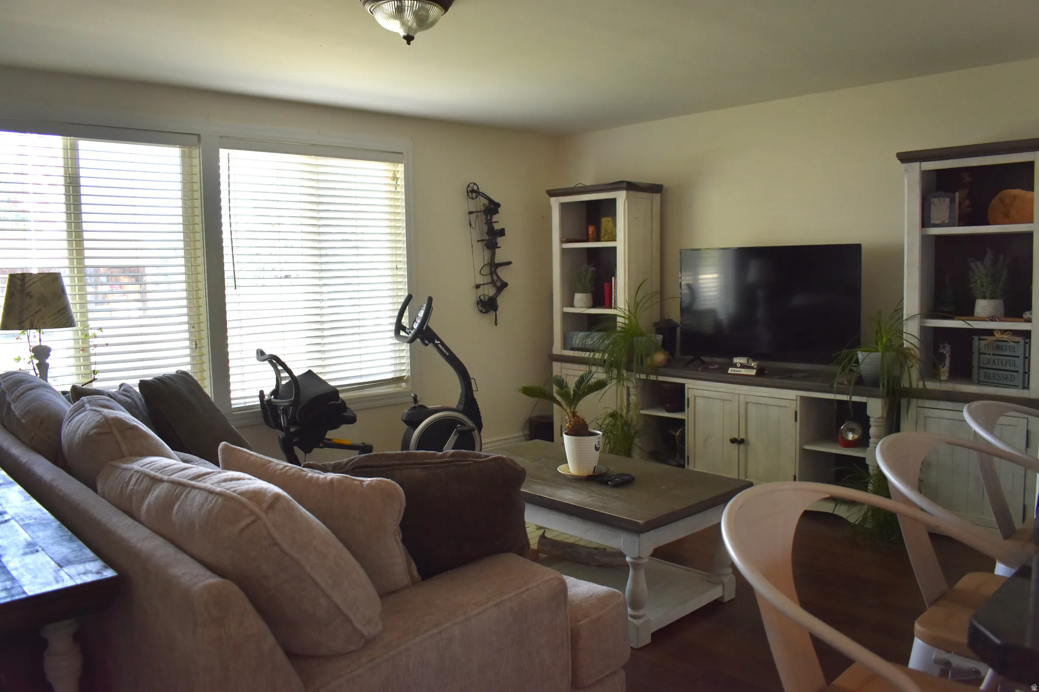 Spacious living area featuring large windows with blinds, wood-finish flooring, and a neutral wall color