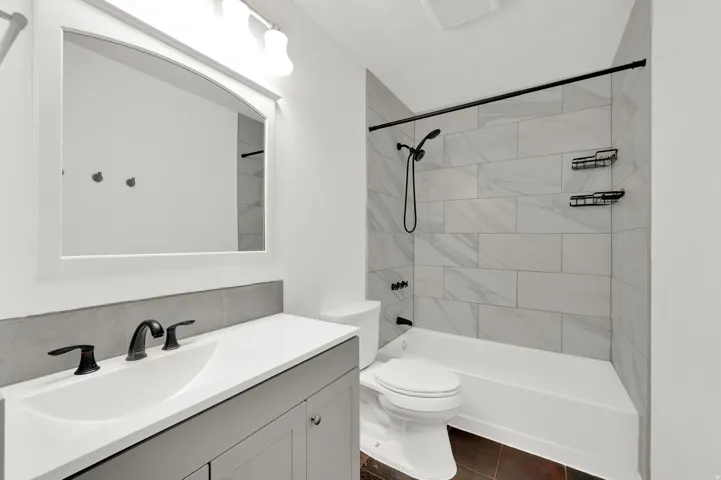 Modern bathroom featuring a single vanity with dark gray cabinetry, integrated sink, and matte black fixtures