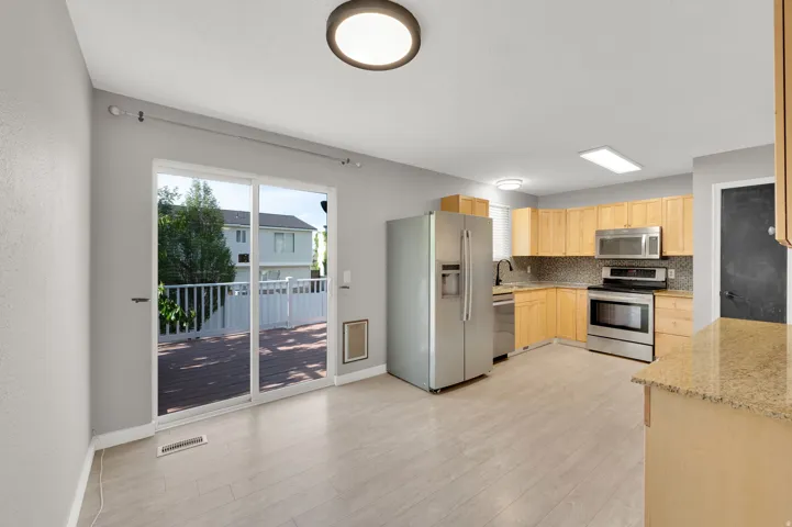 Kitchen featuring stainless steel appliances, light wood-finish cabinetry, and a granite-look countertop