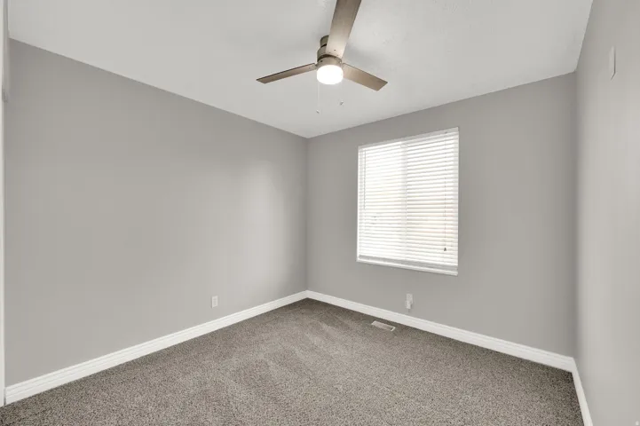 Interior room featuring neutral gray walls, textured carpeting, and white baseboards