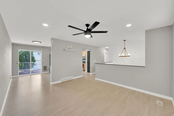Open concept living area featuring light wood-finish flooring, a contemporary black ceiling fan, and recessed lighting