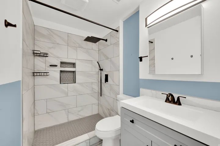 Bathroom featuring a walk-in shower with large format tile walls and a hexagonal tile floor