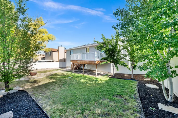 Spacious backyard featuring a two-story residence with a wood-finish deck and white railings