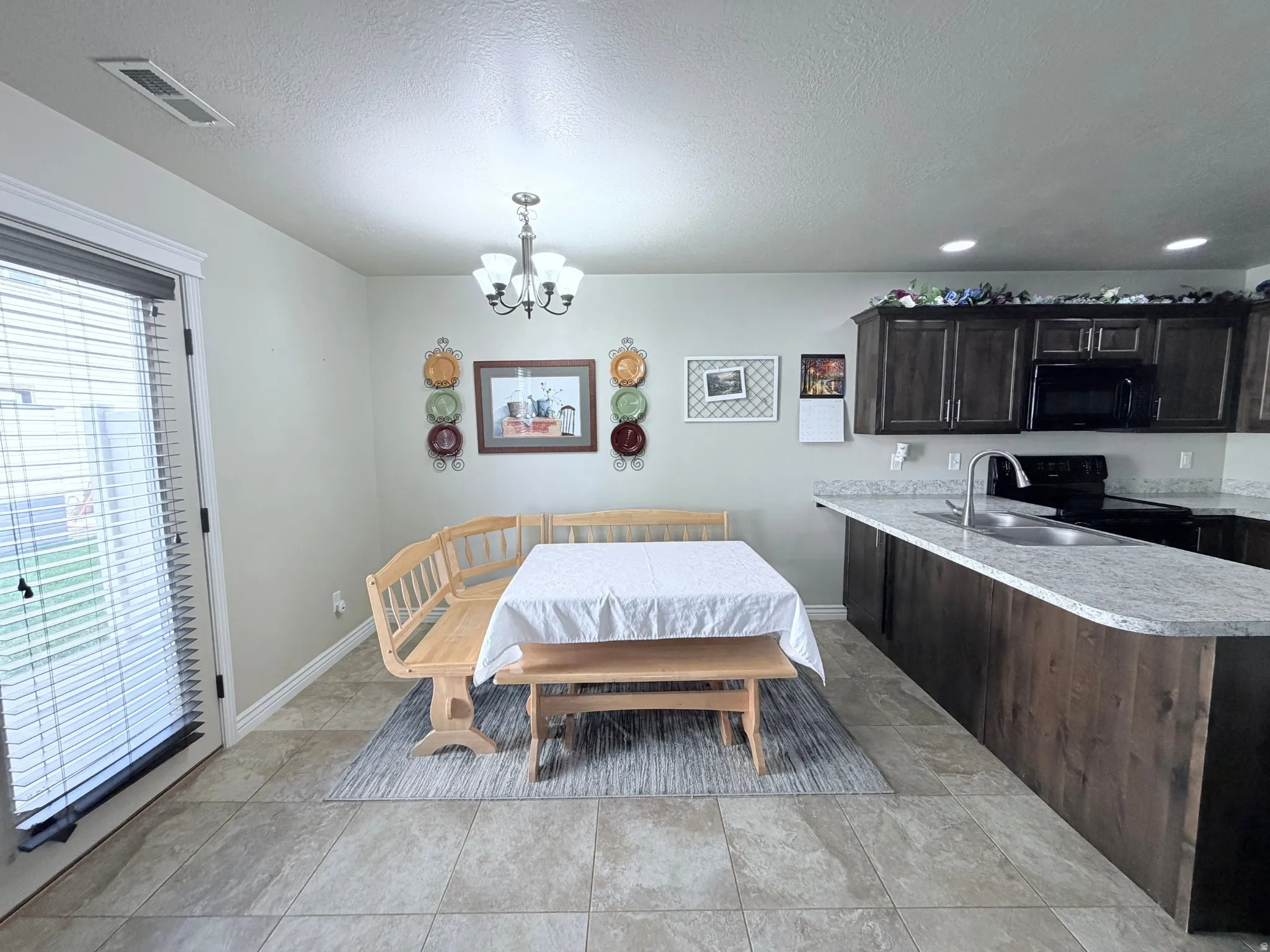 Kitchen and dining area featuring tile flooring, dark wood-finish cabinetry and light-toned countertops