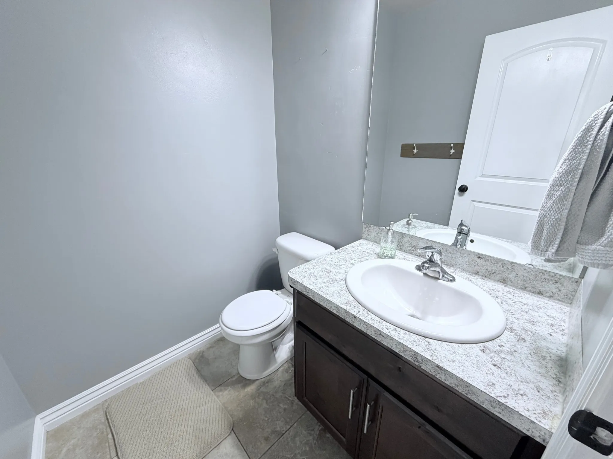 Half Bathroom on main level featuring a dark wood-finish vanity with an integrated white sink and a light countertop