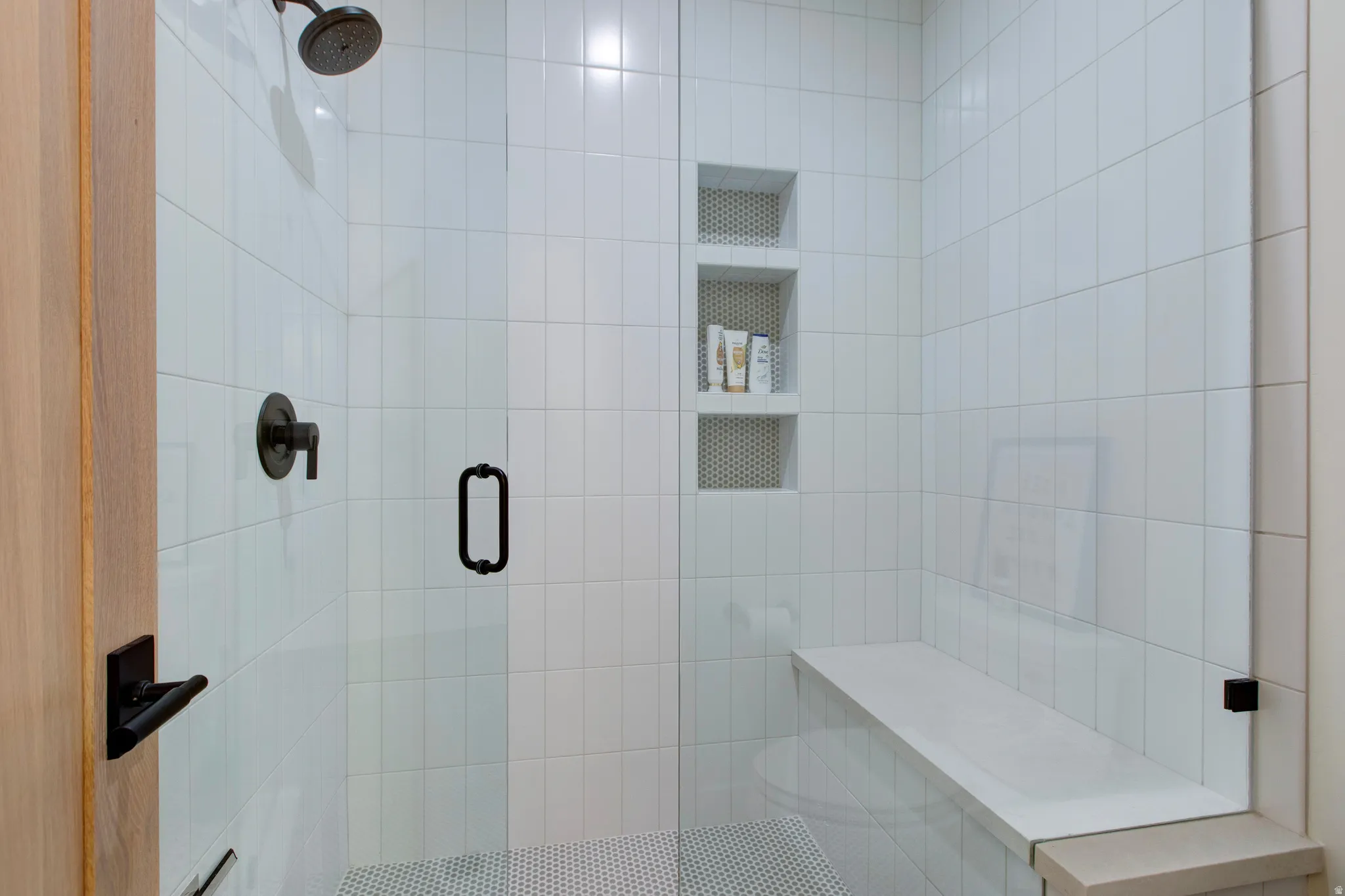 Walk-in shower featuring white subway tile, a dark bronze rainfall showerhead, and a frameless glass enclosure
