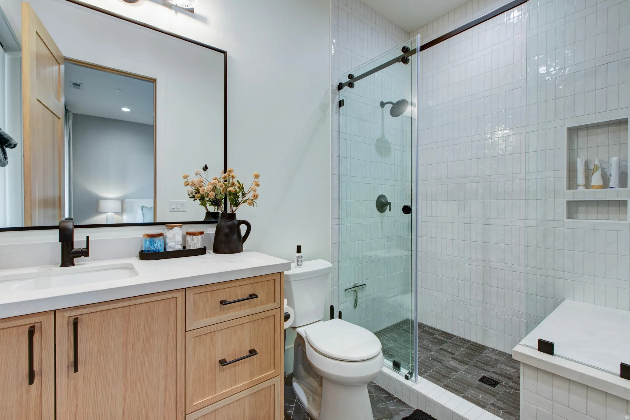 Contemporary bathroom featuring a light wood-finish vanity with integrated sink and dark hardware