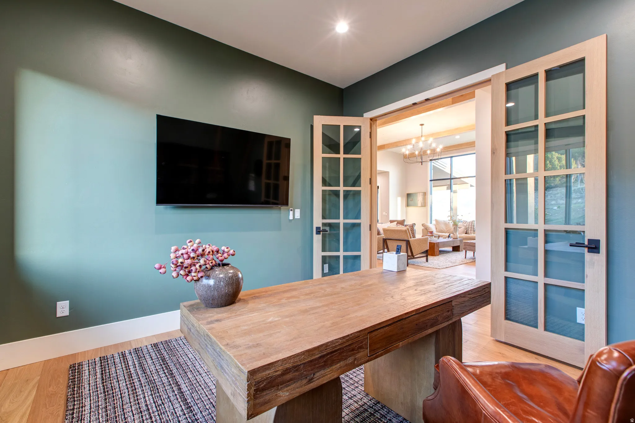 Room featuring a wall-mounted television, wood-finish flooring, recessed lighting, and a substantial wooden desk