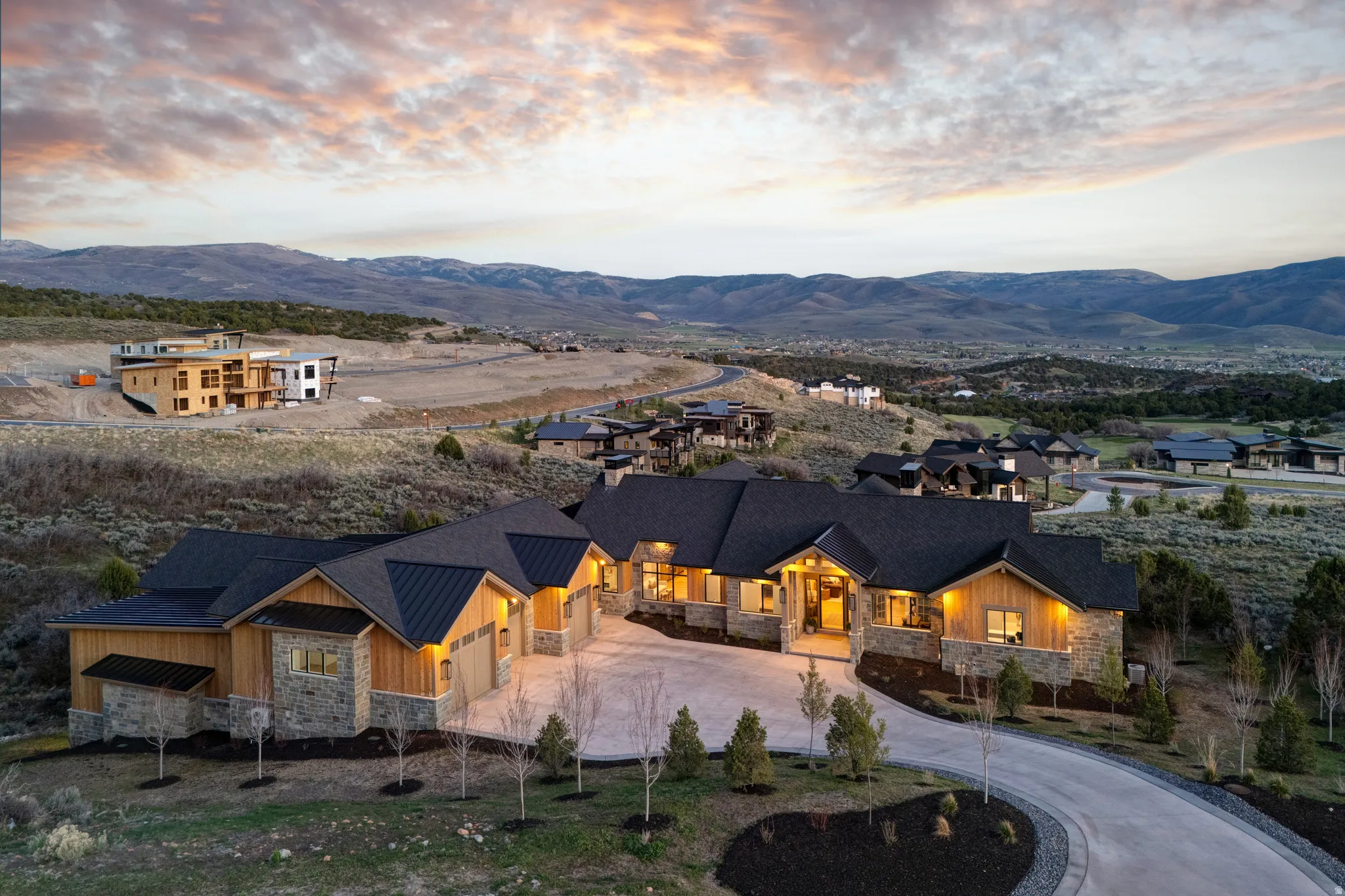 Ranch-style residence featuring stone and wood siding, a dark pitched roof, and a circular driveway