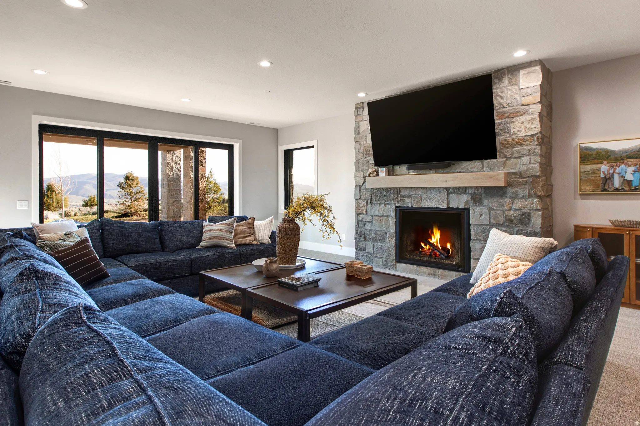 Spacious living area featuring a stone-clad fireplace with a wood mantel, recessed lighting, and large sliding glass doors