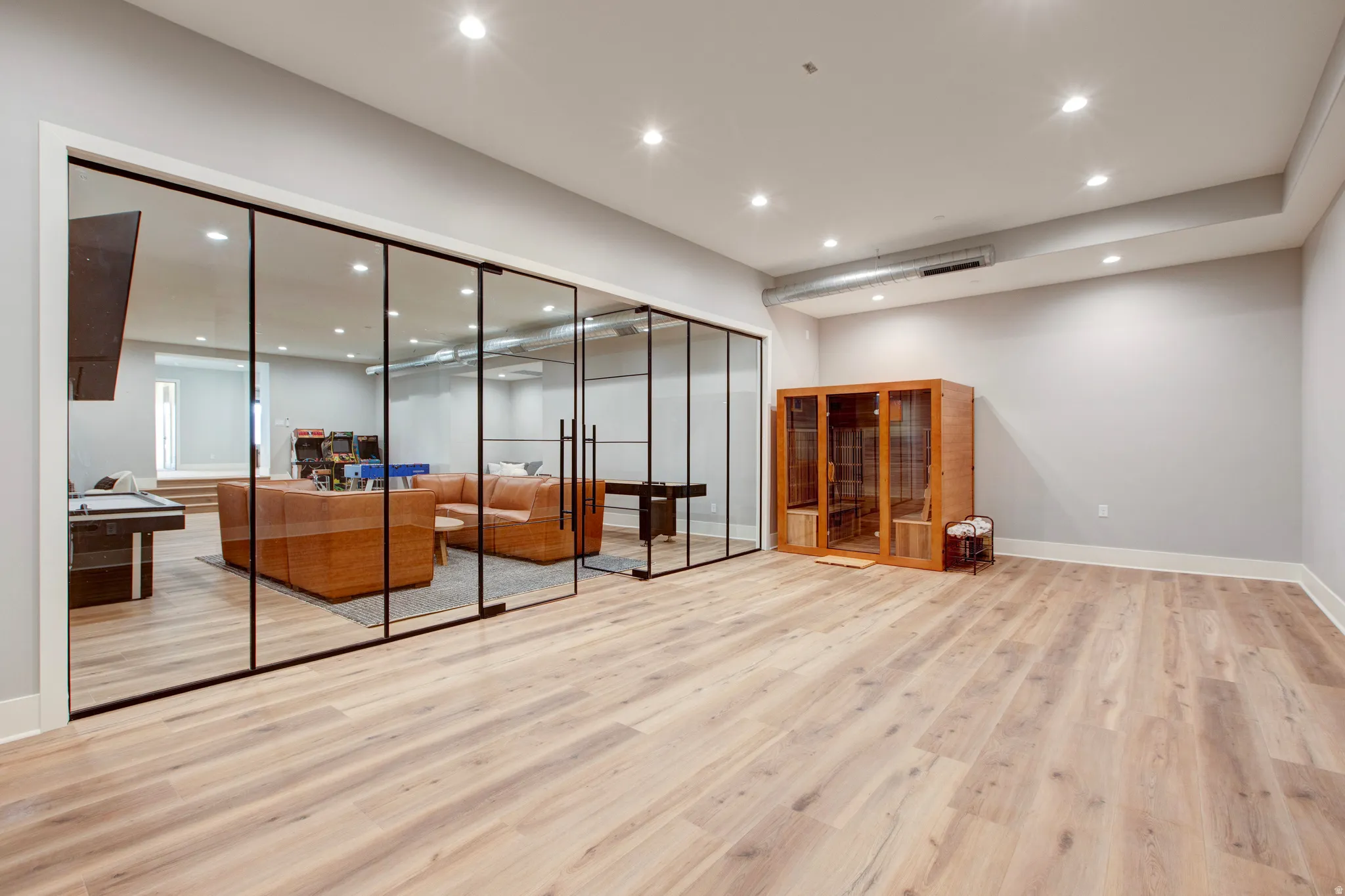 Spacious room featuring light wood-finish flooring, recessed lighting, and a built-in sauna