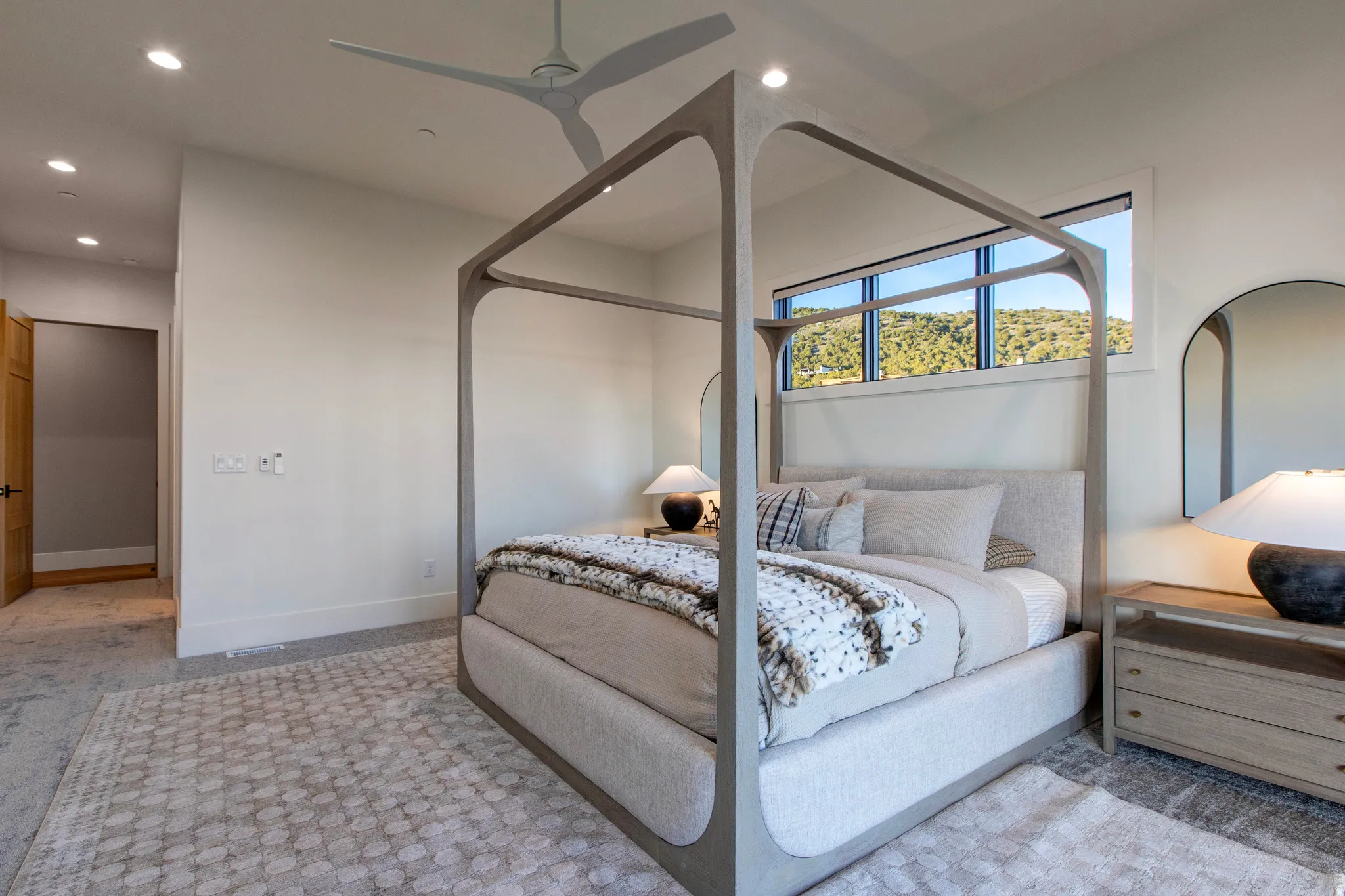Bedroom featuring a contemporary ceiling fan, recessed lighting, and a panoramic window showcasing distant hills