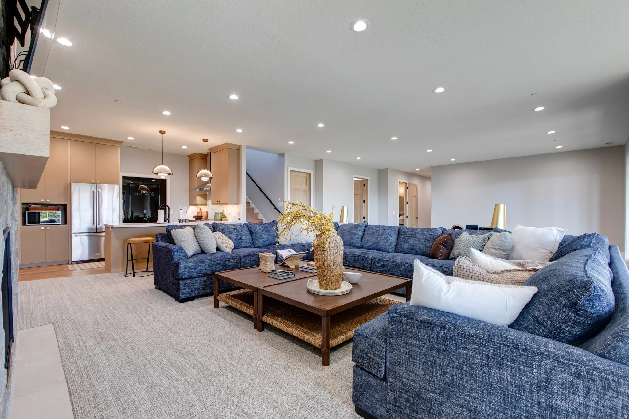 Open-concept living space featuring recessed lighting, light-toned carpeting, and a stone-clad fireplace