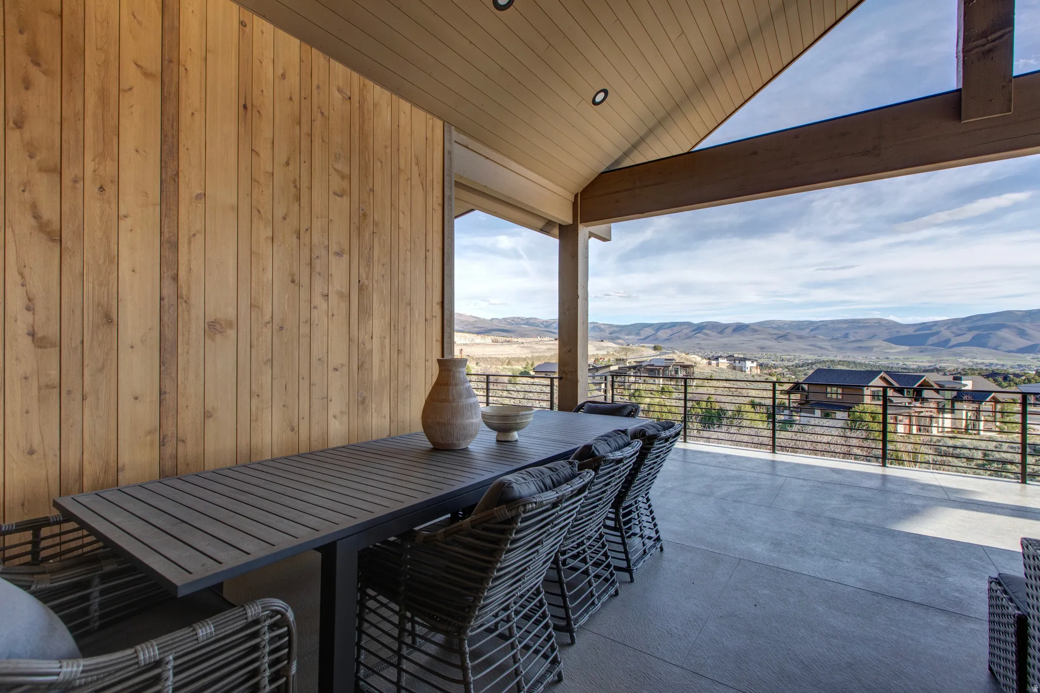 Expansive covered patio featuring a concrete floor, slatted wood-finish wall, and an exposed wood beam ceiling with recessed lighting