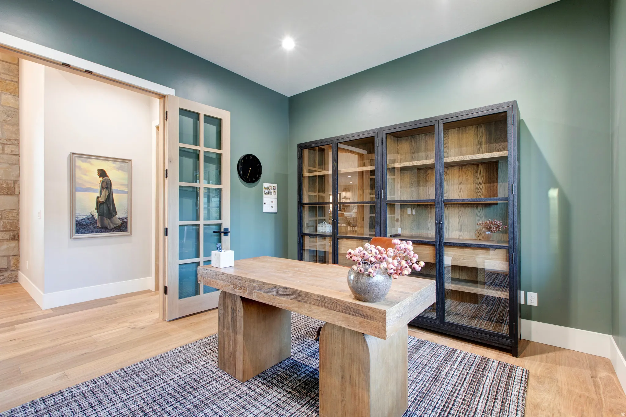 Home office featuring light wood-finish flooring, a contemporary wood desk, and an accent wall