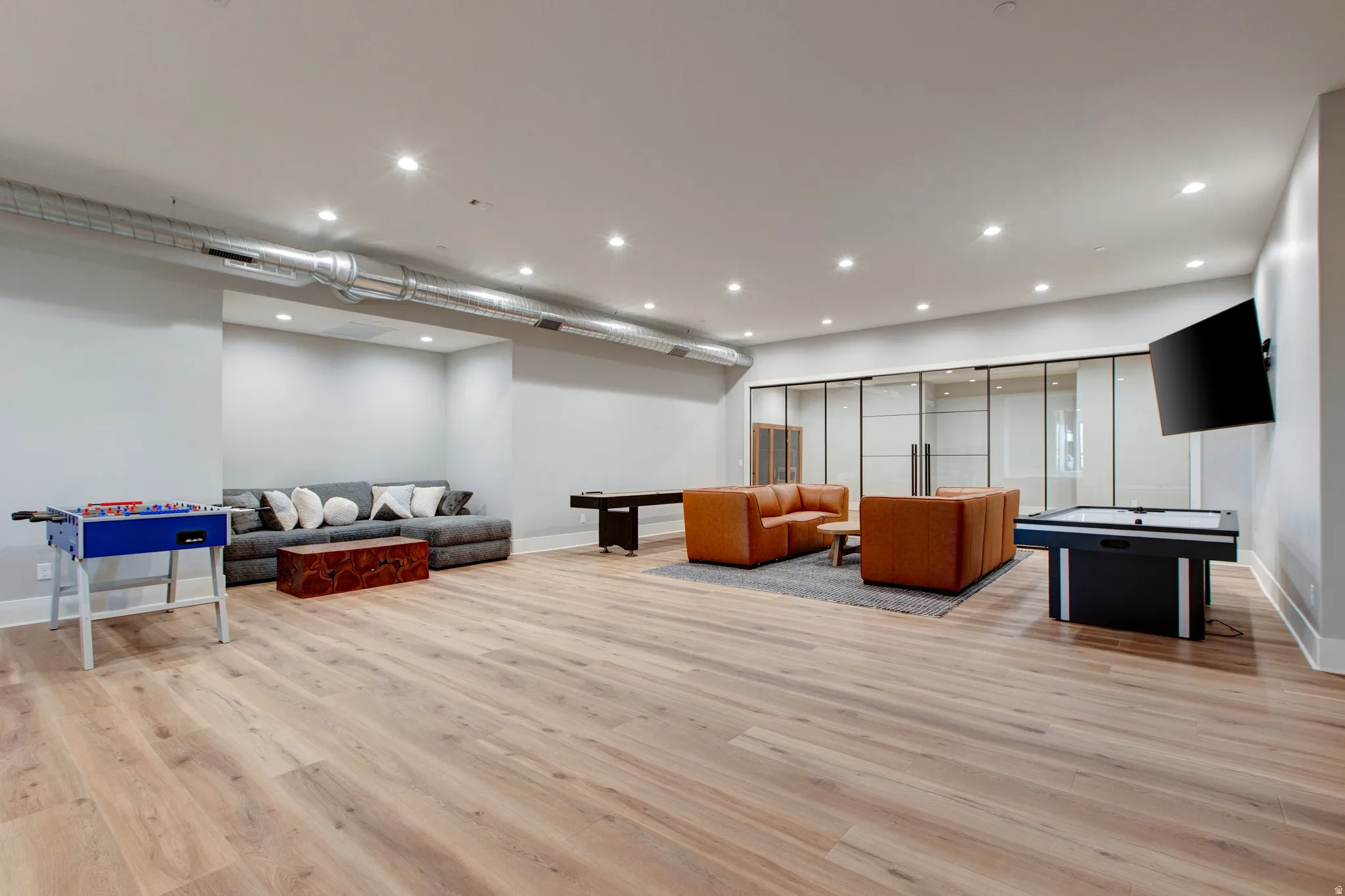 Spacious multi-purpose room featuring wood-finish flooring, recessed lighting, and exposed ductwork