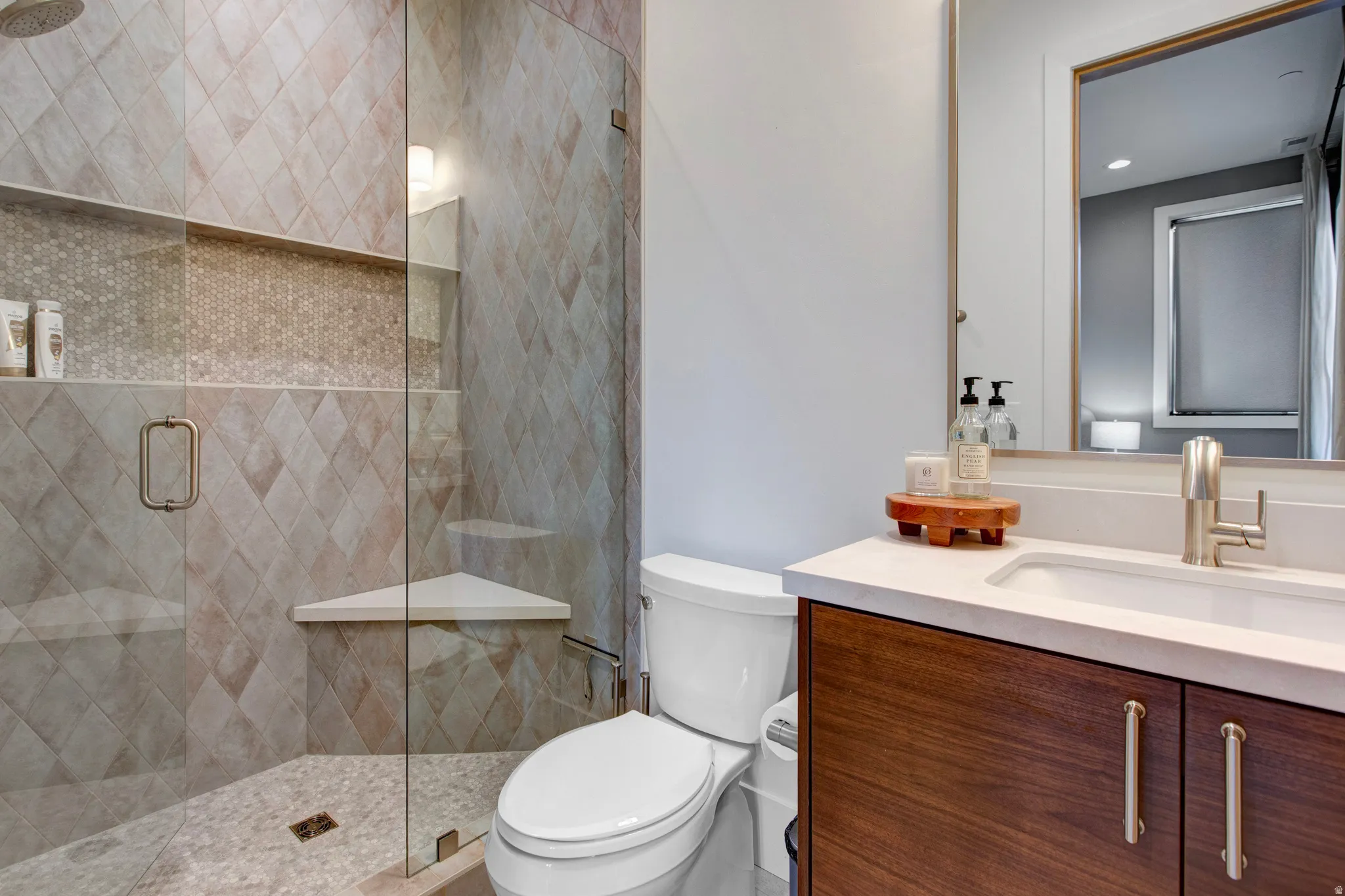 Contemporary bathroom featuring a glass-enclosed shower with diamond-patterned tile, a built-in shower niche with mosaic accents, and a corner shower bench