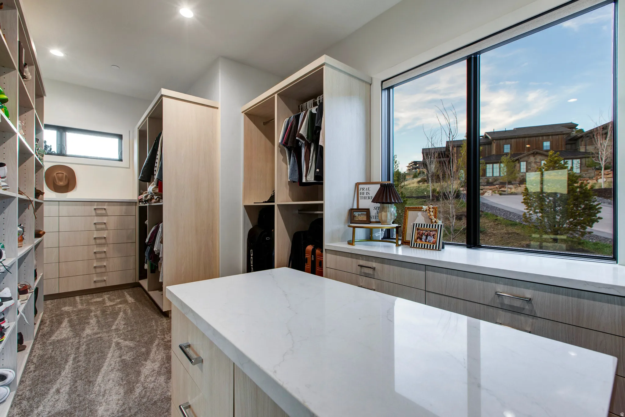 Custom closet featuring a central island with a stone countertop, built-in shelving, drawers, and hanging storage