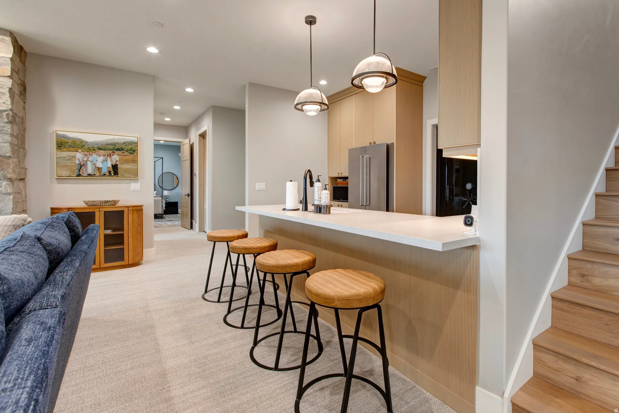 Contemporary kitchen bar featuring a light-toned countertop, pendant lighting, and light wood cabinetry with stainless steel appliances