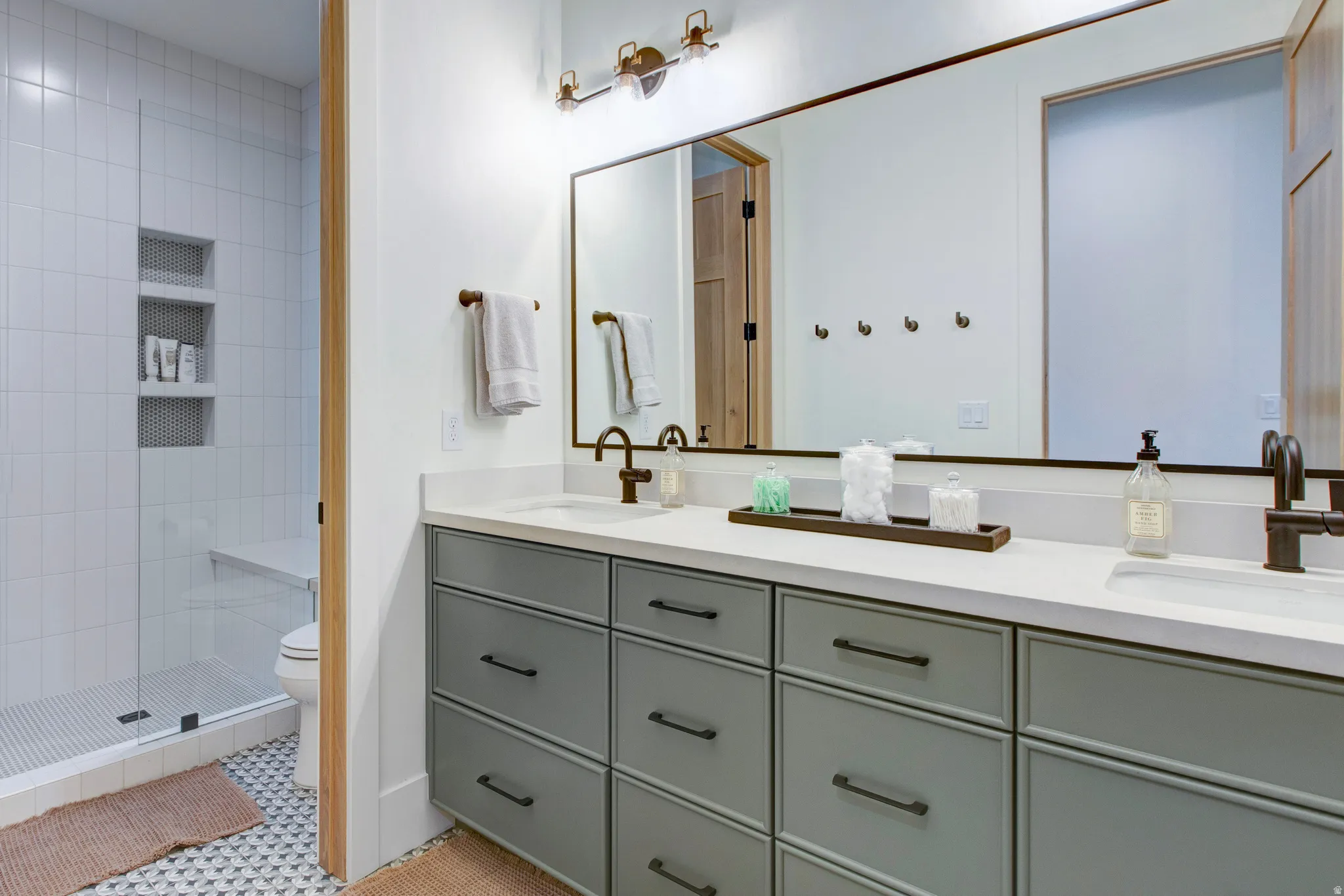 Dual vanity with light gray cabinetry, matte black hardware, and an expansive countertop