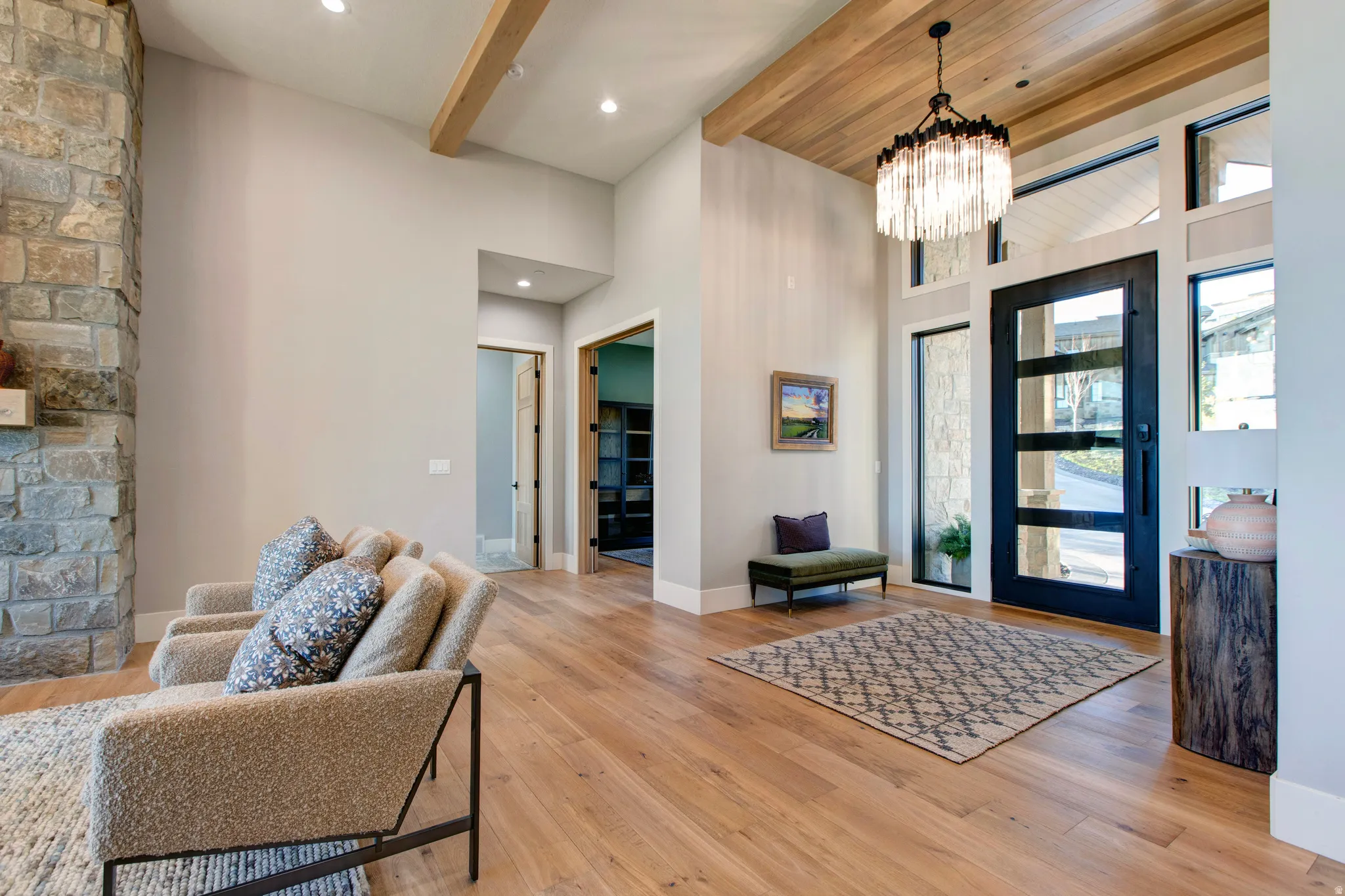 Grand entryway featuring a black-framed glass panel door, wood-finish flooring, and a stone-clad fireplace