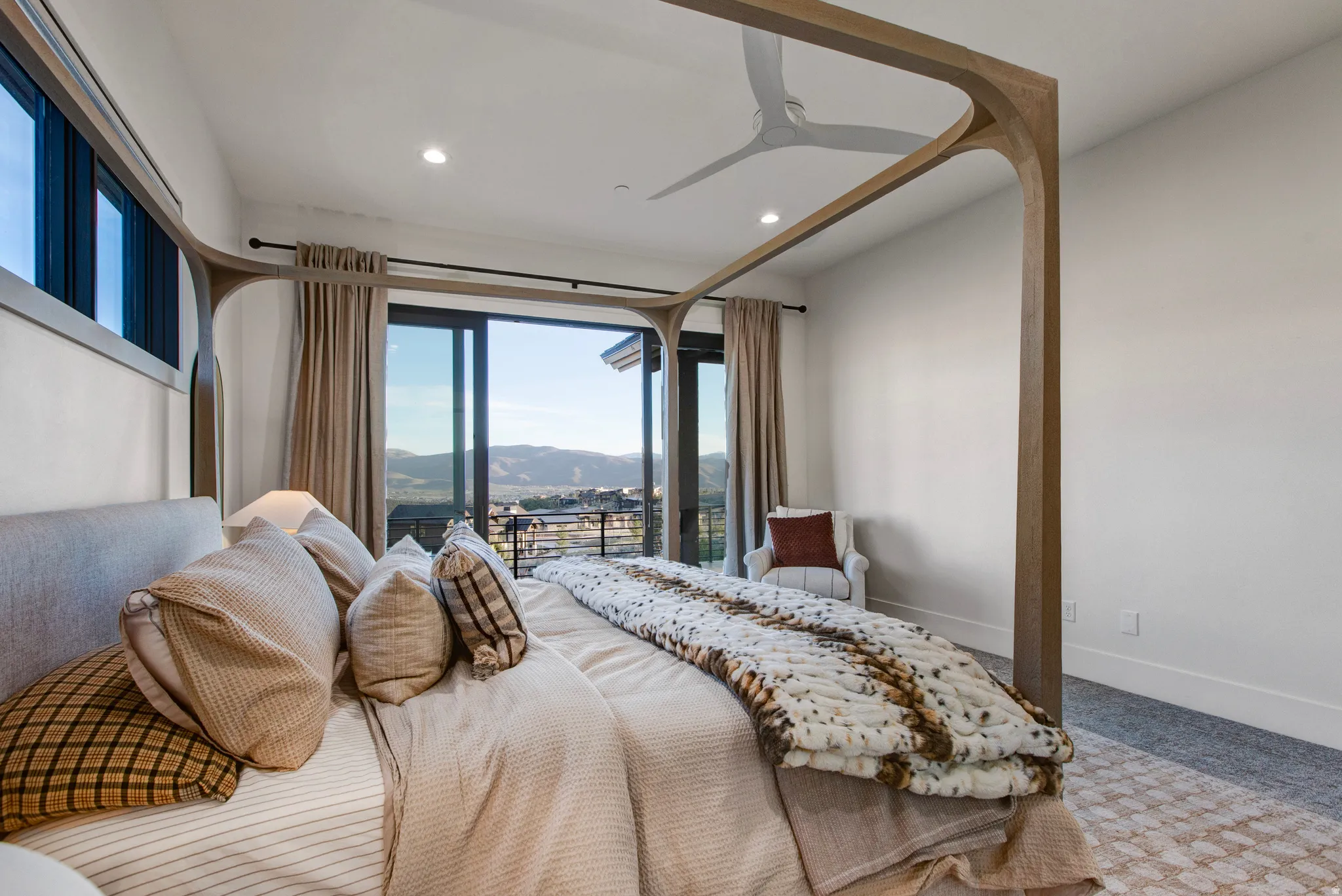 Bright sleeping area featuring a sliding glass door to a balcony, high ceilings with recessed lighting, and a modern ceiling fan