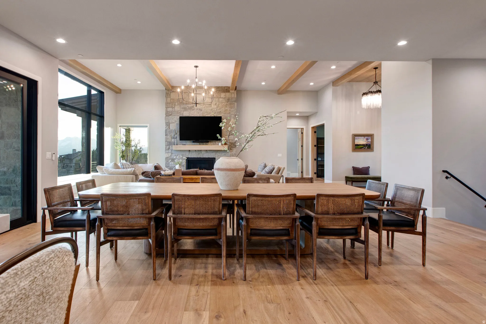Open-concept living space with light wood-finish flooring, recessed lighting, and exposed ceiling beams