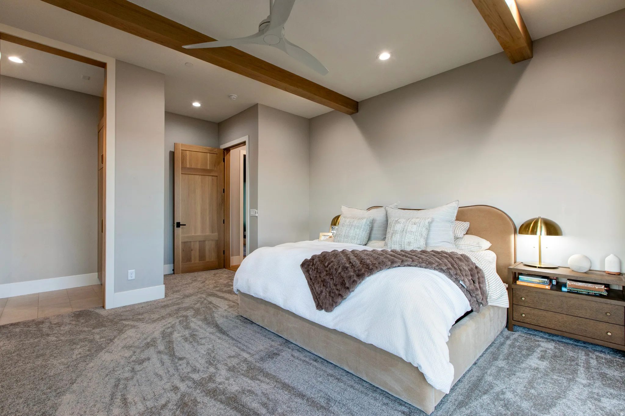 Spacious room featuring exposed wood ceiling beams, recessed lighting, and a neutral color palette