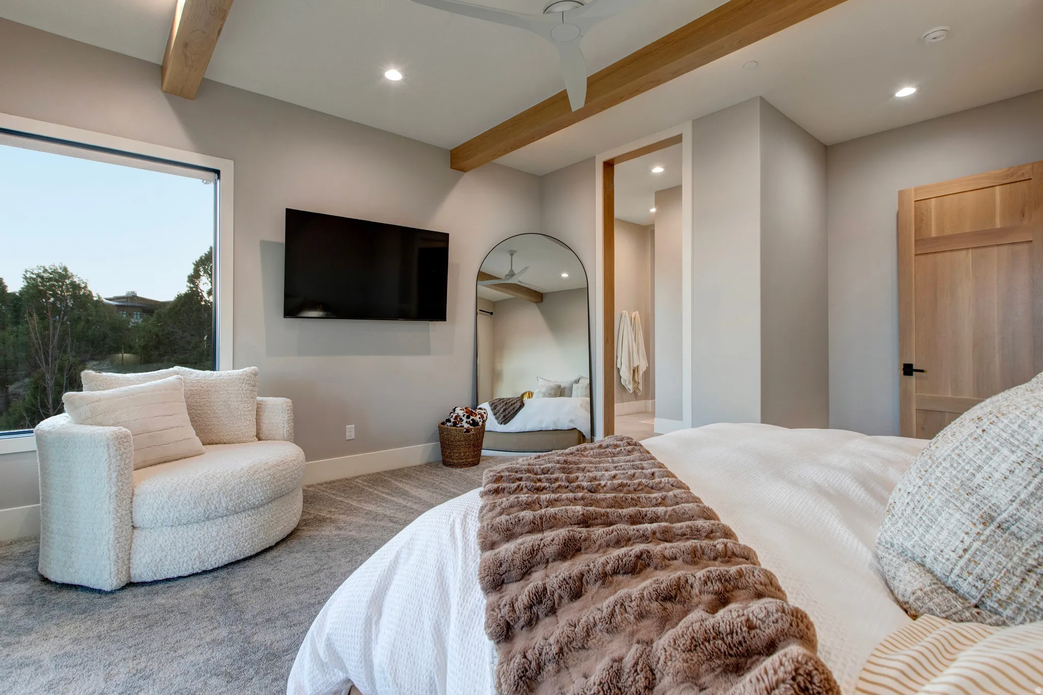 Spacious room featuring exposed wood ceiling beams, recessed lighting, a large picture window, and a built-in wall-mounted television
