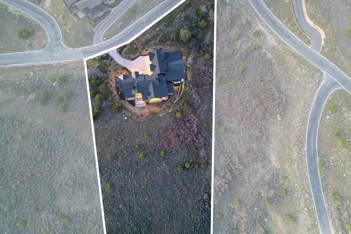 Residential property featuring a multi-level roofline, extensive paved driveway, and established surrounding foliage