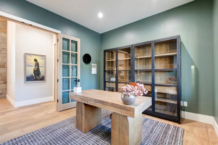 Home office featuring light wood-finish flooring, a contemporary wood desk, and an accent wall