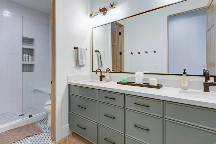 Dual vanity with light gray cabinetry, matte black hardware, and an expansive countertop
