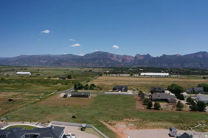 Expansive rural landscape featuring distant mountain ranges and scattered residential properties