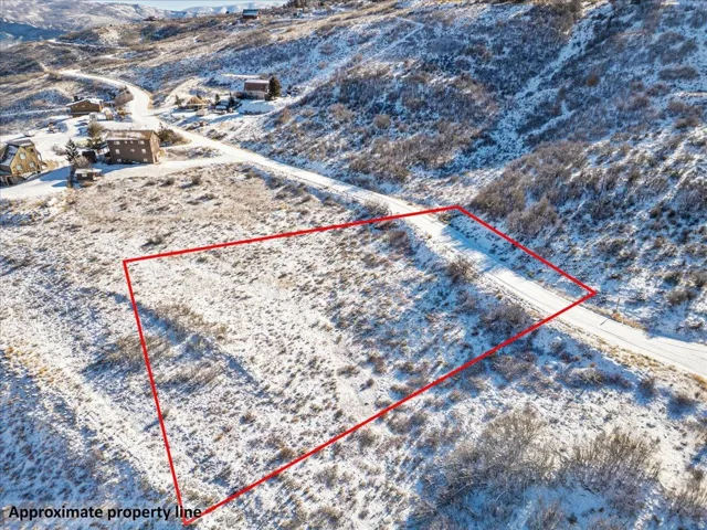 Aerial view of property and surrounding area with property parcel outlined and a mountainous background