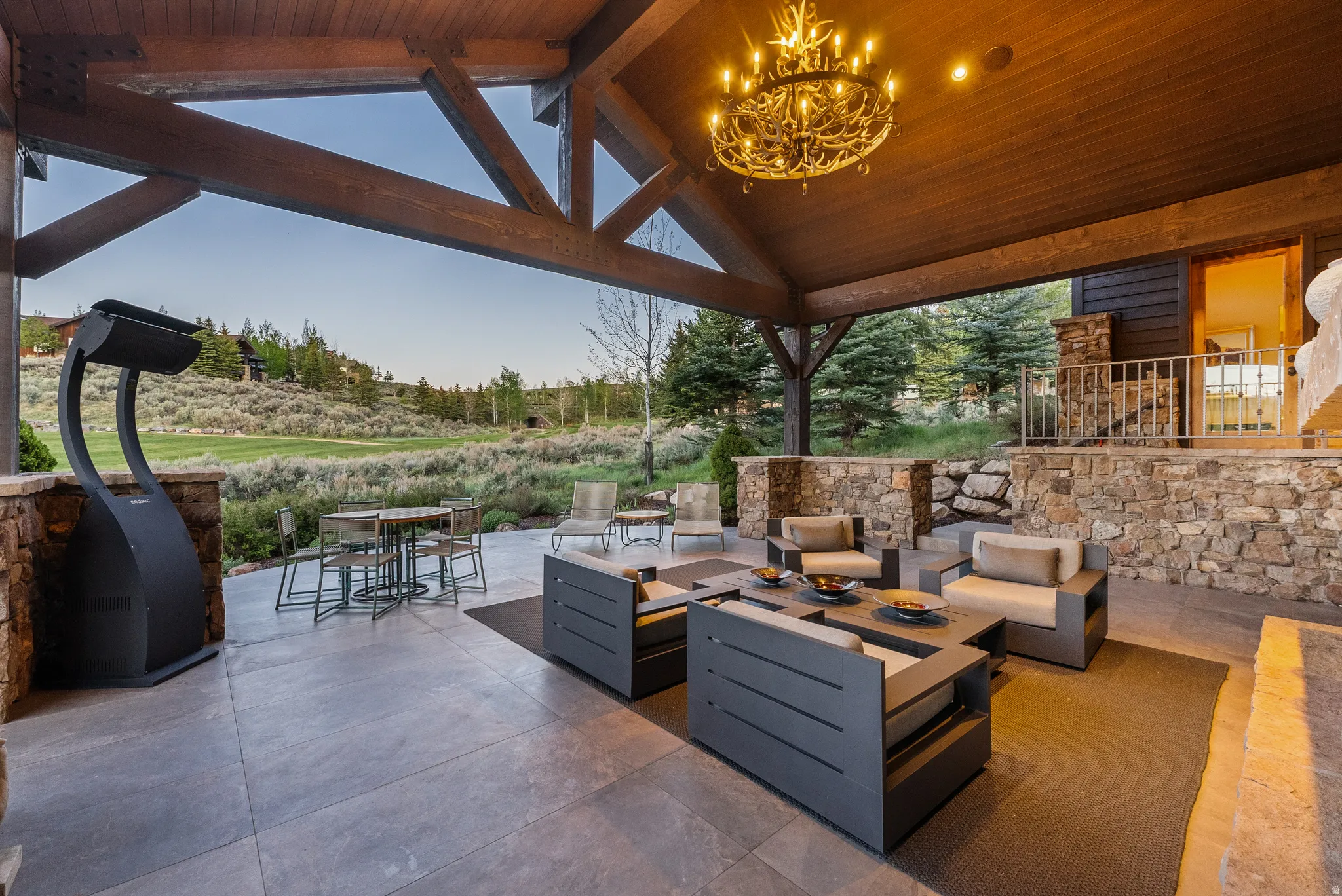 Expansive covered patio featuring a wood-finish ceiling, exposed structural beams, and a decorative chandelier