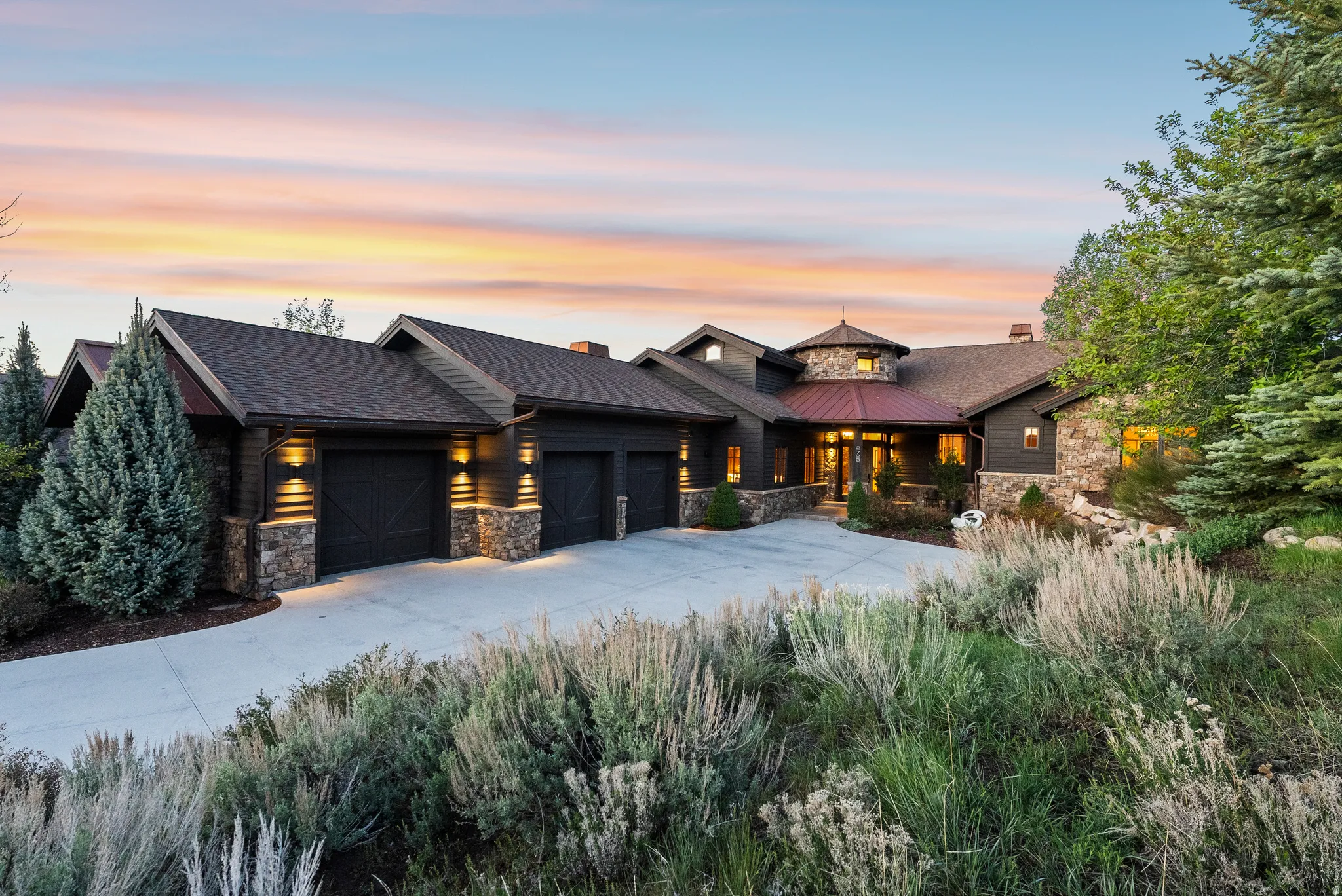 Exterior featuring dark siding, stone accents, and a multi-car garage with carriage-style doors