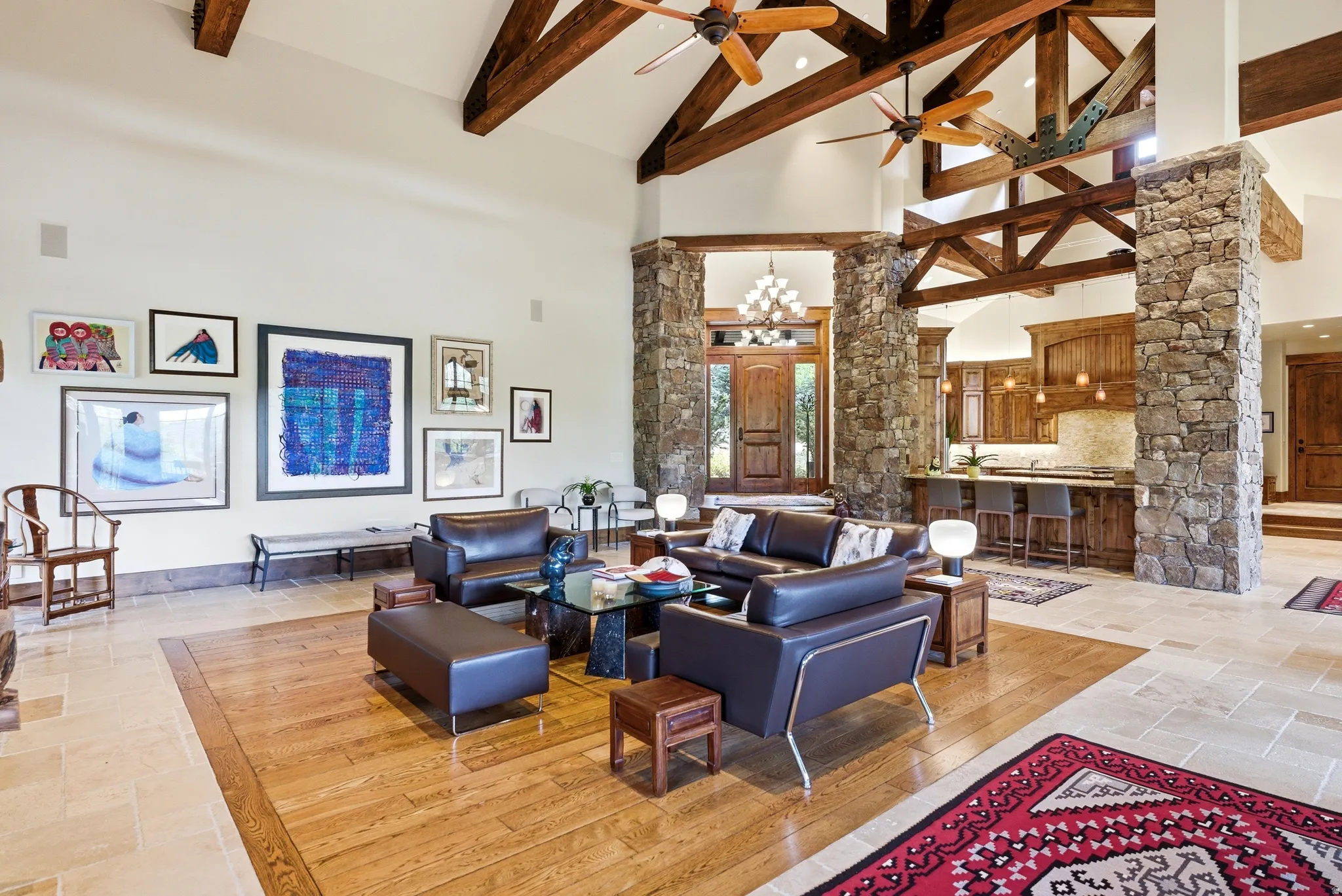 Spacious living area featuring a vaulted ceiling with exposed wood beams and ceiling fans