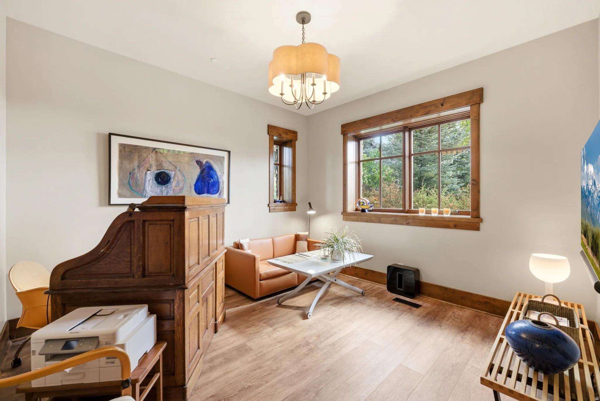 Interior space featuring wood-finish flooring, a large window with natural wood trim, and light-toned walls