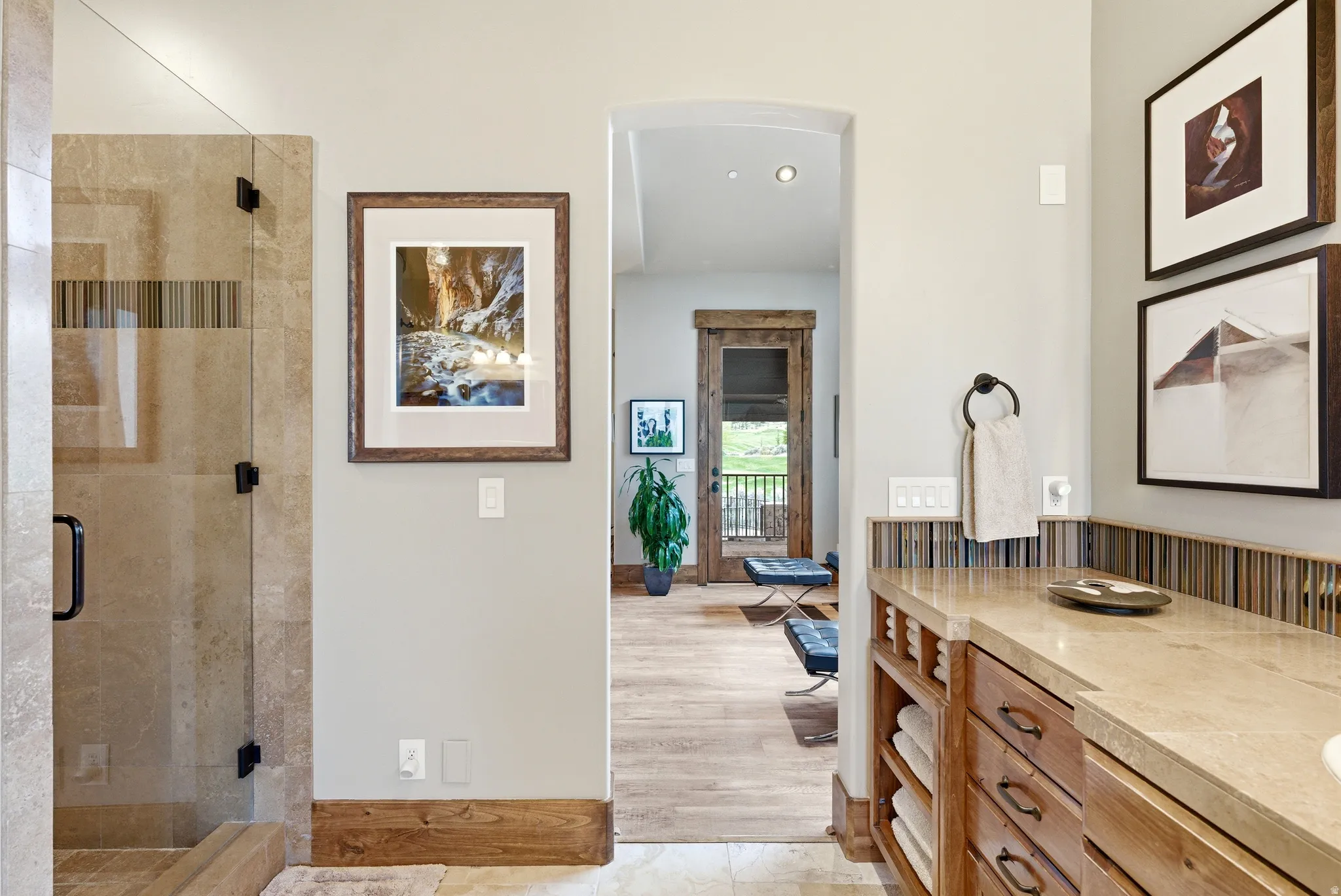 Glass-enclosed shower with stone tile surround and black hardware