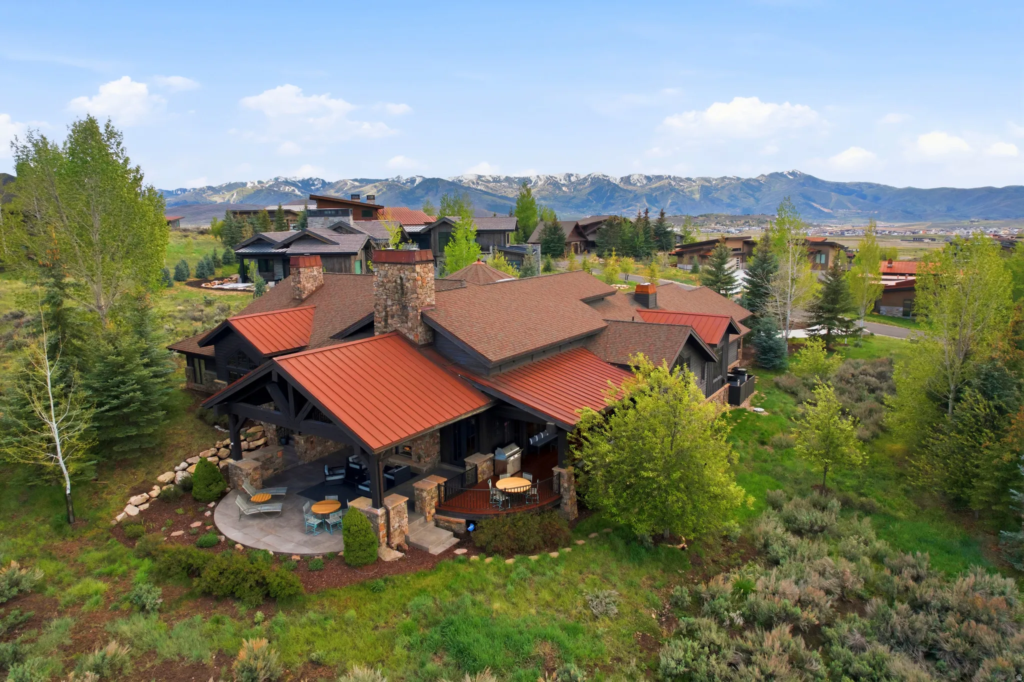 Stone and wood-sided residence featuring a multi-level roofline with both shingle and standing seam metal roofing