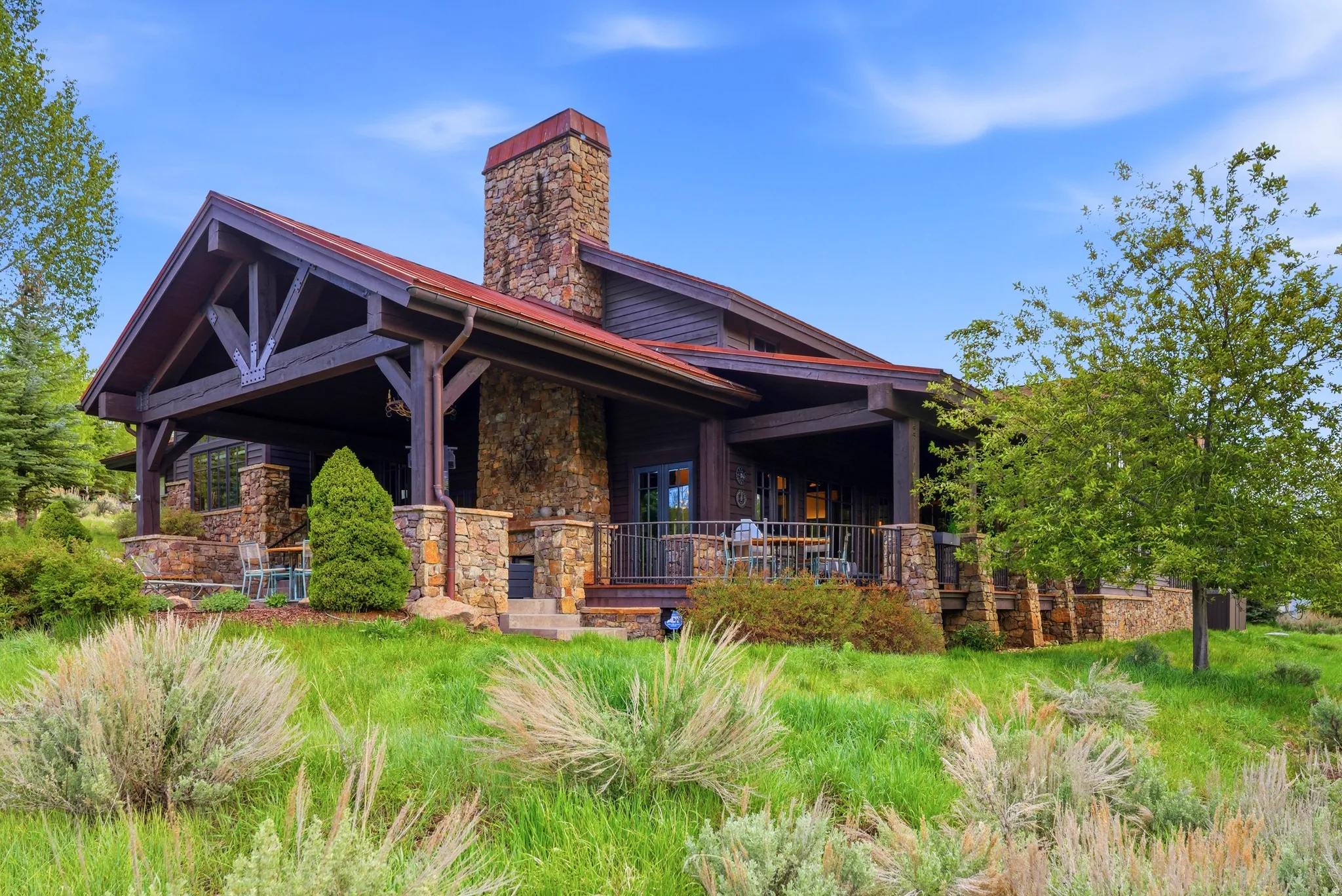 Rustic-style residence featuring a prominent stone chimney and foundation